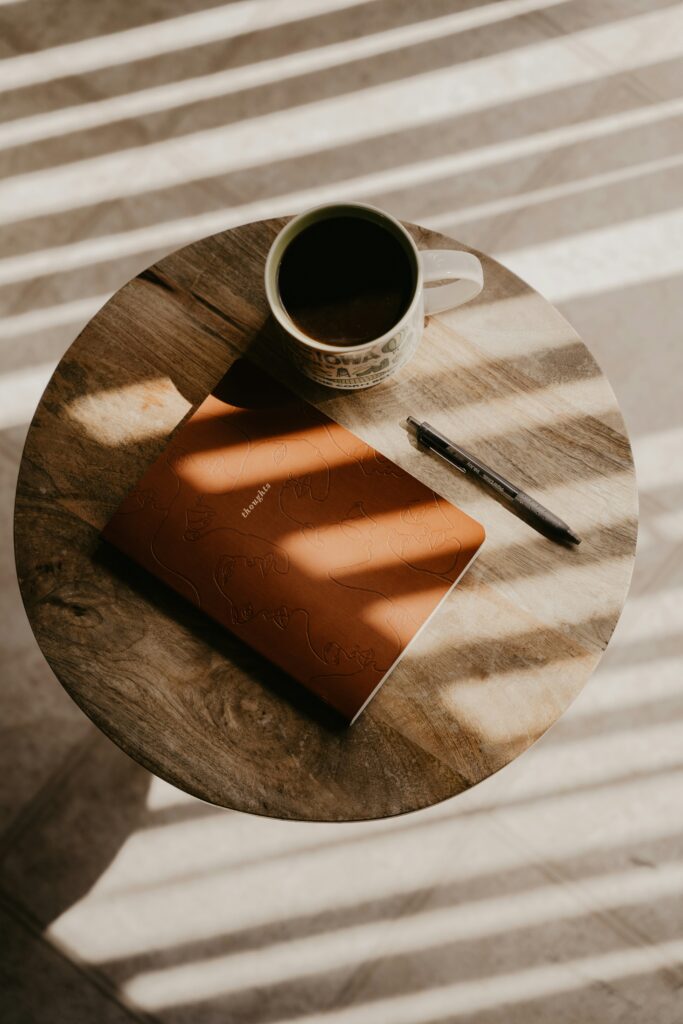 A notebook and coffee cup on a wooden table, representing the Thoughts and Coffee blog - a place for honest reflections on leadership and work